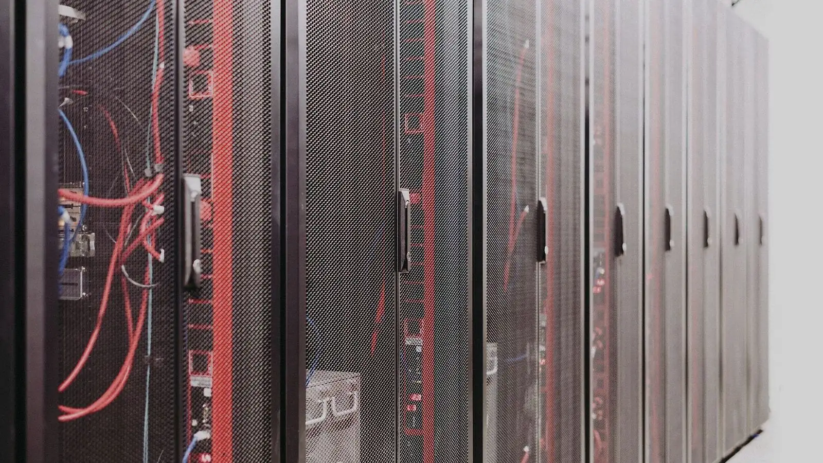 Fileira de racks de rede em sala técnica com cabeamento organizado nas laterais