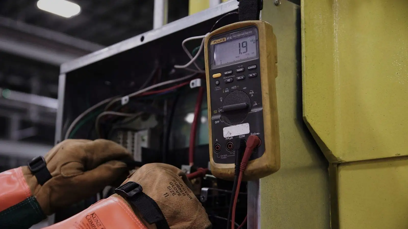 Medição com multímetro em painel de controle industrial durante manutenção elétrica
