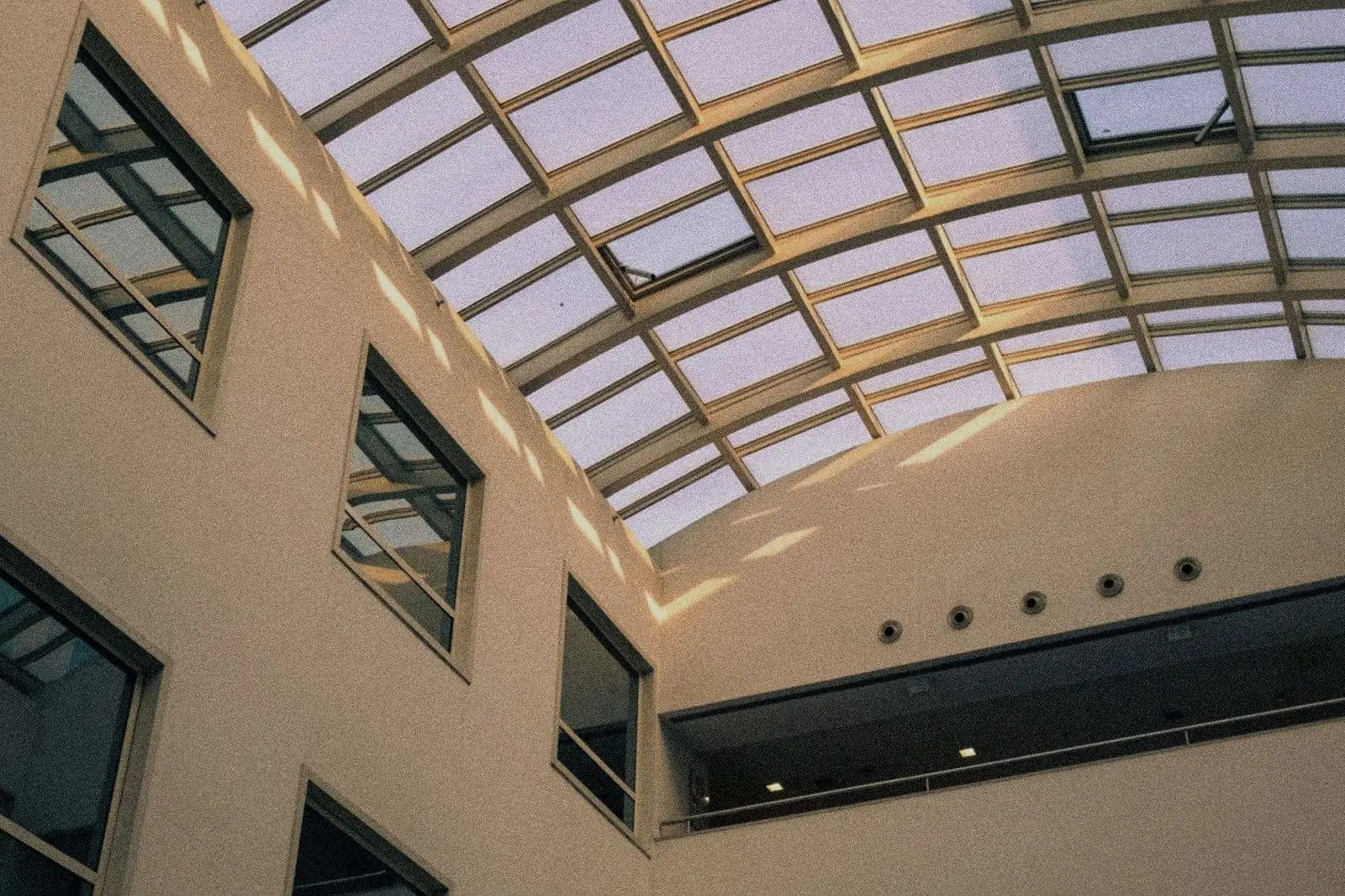Átrio de edifício corporativo com cobertura de vidro e estrutura metálica aparente