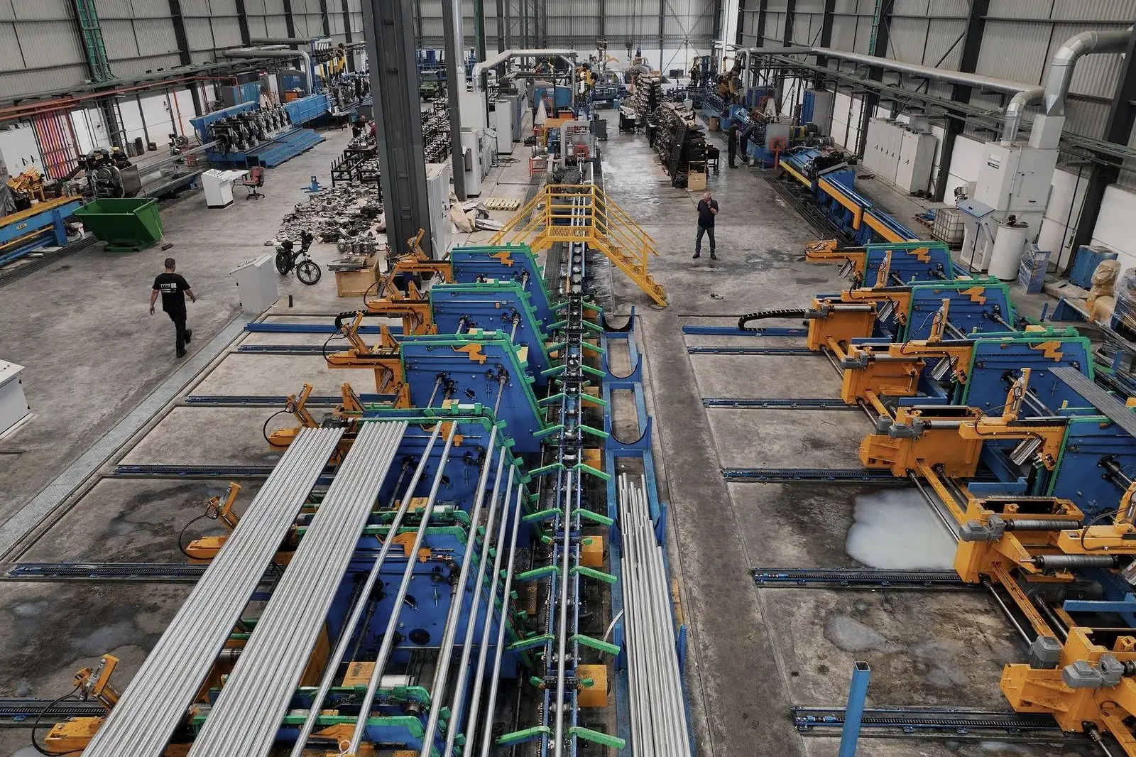Vista elevada de planta industrial com linhas de produção, equipamentos e circulação de equipes